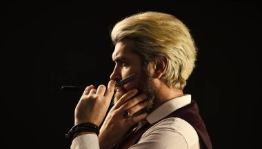 Bıyıklı beyaz bir hippi. Berber dükkanında bir erkek. Saçları sarıya boyanmış olgun bir adam. Klasik berber stili. Berber aletleri. Berber aletleri ve erkek aksesuarları. Hippi Berber Adam