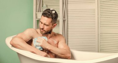 Arzu ve cazibe. Adam kaslı vücudu süngerle yıkıyor. Kişisel bakım. Banyodaki seksi adam. Maço adam banyoda yıkanıyor. Hijyen ve sağlık. Sabah duşu. Sağlıklı erkek yaşam tarzı.