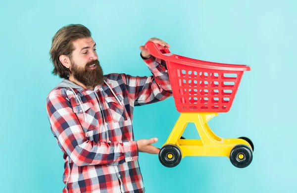 successful shopping day. male shopper with shopping cart. bearded guy in checkered shirt do purchase. unshaven brutal man with beard. buy products in mall. everyday duties and routine