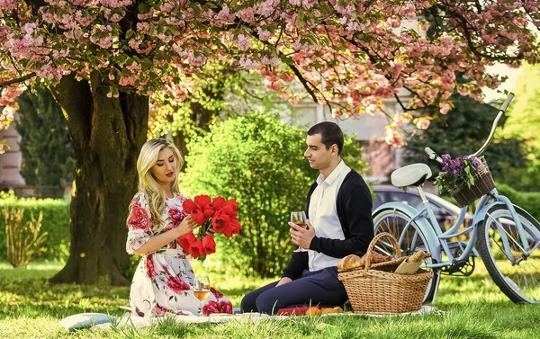 Gemeinsam glücklich. Verliebtes Paar beim Picknick. Frühlingswochenende. Blumen symbolisieren Romantik und Zuneigung. Genießen ihr perfektes Date. Paar entspannt sich im Park mit Fahrrad. Romantisches Picknick mit Wein — Stockfoto