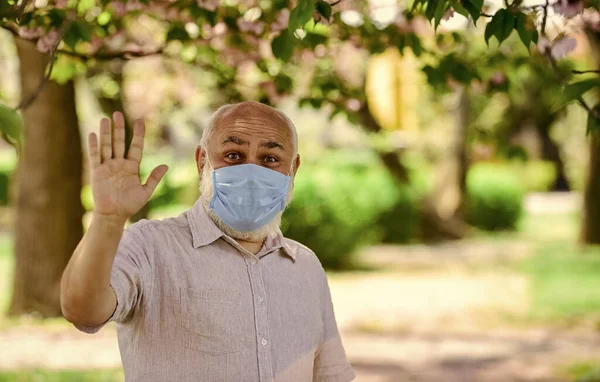 Ondersteuning van ouderen tijdens coronavirus lockdown en sociale afstand. Veiligheidsmaatregelen. Coronavirus pandemie. Senior man met gezichtsmasker. Pandemisch concept. Stop de pandemie. Raak je gezicht niet aan. — Stockfoto