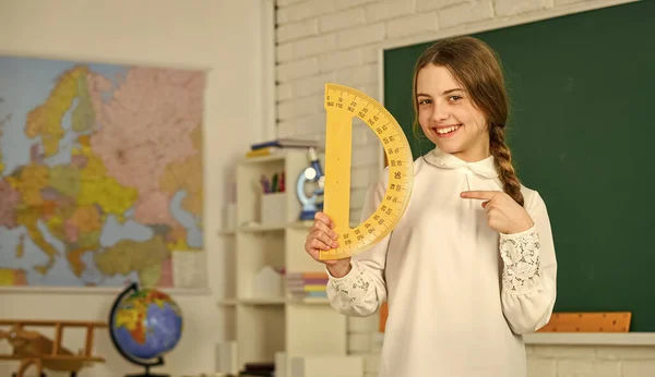 Vamos estudar juntos. Aprender a usar transferidor. de volta à escola. Estudante do ensino médio aprendendo geometria em sala de aula. medir ângulos. Menina criança pequena segurando escola transferidor para lição de geometria — Fotografia de Stock