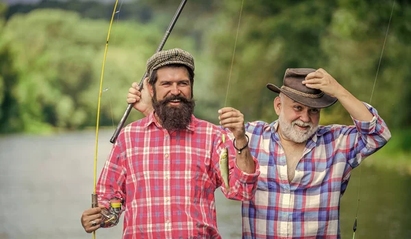 La famiglia è la migliore. hobby e attività sportive. Esche di trota. weekend estivo. uomini maturi pescatore. padre e figlio pesca. due pescatori felici con canne da pesca. amicizia maschile. legame familiare — Foto Stock