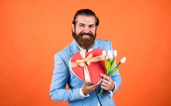 Взрослый бородатый мужчина выглядит элегантно с весенними тюльпанами, свидание — стоковое фото