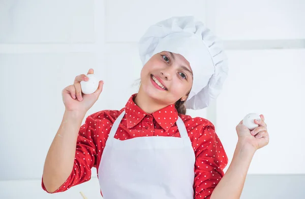 Faire de la nourriture spéciale. heureuse adolescente tenant des œufs. enfant porter uniforme de chef dans la boulangerie — Photo