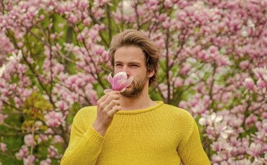 Bahar ilham. Baharın neşesi. Bahar güzeli. Modern hipster çiçekleri sever. İlkbahar konsepti. Adam çiçek parkında rahatlıyor. Botanik bahçesi. Erkek çiçek arka planı. Tazelik ve uyanış