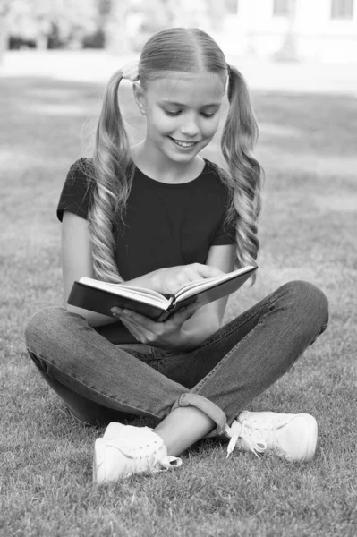 Menina pequena penteado bonito leitura livro relaxante natureza fundo, conceito de conto de fadas favorito — Fotografia de Stock