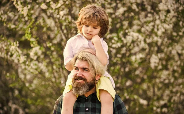 Dad and son. Little son. Spring walk. Fatherhood. Happy family. Fathers day. Little boy and father in nature background. Hipster and baby son in blooming garden. Bearded brutal man good father