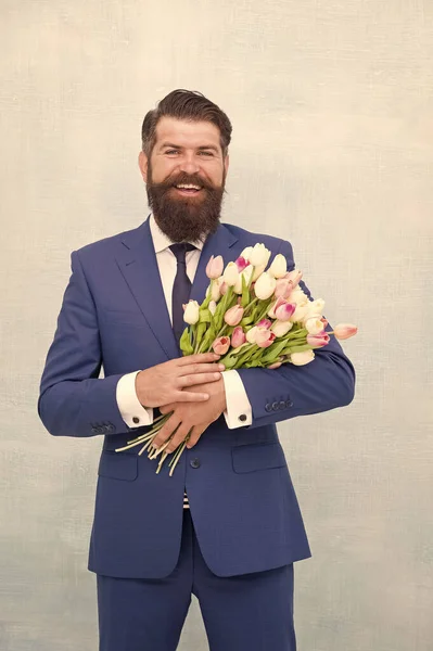 Making surprise. Gentleman with tulips. Spring is coming. Greetings. Bearded man with tulip bouquet. Love date. Womens day. March 8. Spring gift. Bearded man hipster with flowers. Celebrate spring