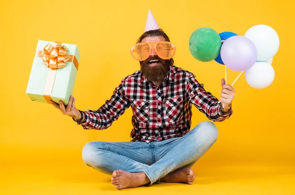 Lustige brutale bärtige Mann tragen kariertes Hemd mit üppigem Bart und Schnurrbart halten Party-Luftballons und Geschenkbox, Geburtstag — Stockfoto