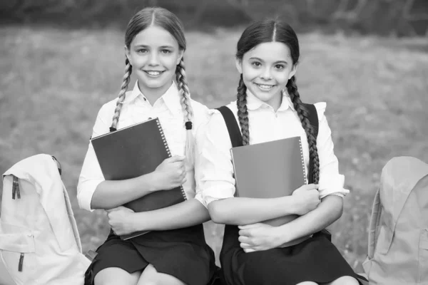 Niñas pequeñas con libros y mochilas. los niños sostienen el cuaderno para tomar notas. Feliz infancia. de vuelta a la escuela. alumnos adolescentes listos para la lección. prepárate para el examen. estudiar juntos al aire libre — Foto de Stock