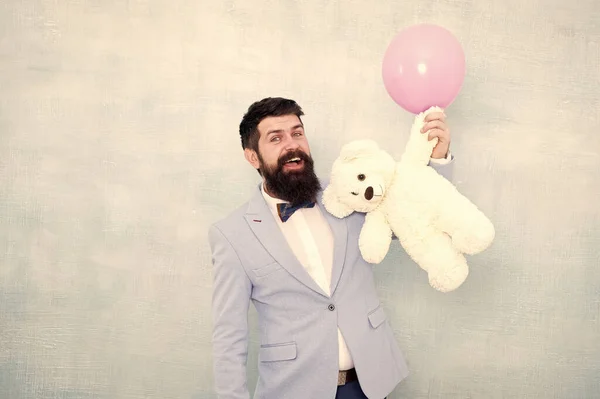 Brutal hipster barbudo em desgaste formal. homem de negócios segurar urso brinquedo e balão. smoking homem pronto para encontro romântico. Presente do dia dos namorados. Feliz aniversário. ir para compras de presente. atração secreta — Fotografia de Stock