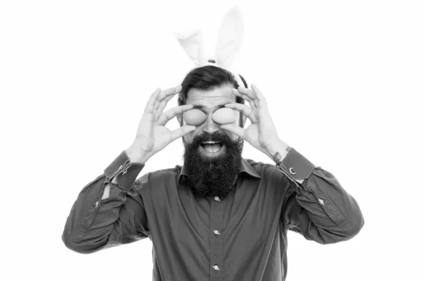 Mira aquí. El hombre de Pascua sostiene los huevos como vasos. El hombre feliz celebra la Pascua. El hombre barbudo usa orejas de conejo. El hombre disfruta de la caza de huevos de Pascua. Celebración festiva. Decoración y tradición para colorear —  Fotos de Stock