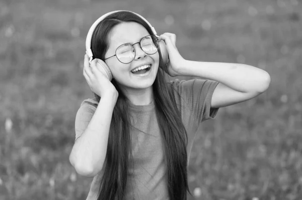 Aggiungere felicità attraverso il canto. Il cantante felice canta canzoni sull'erba verde. Alla bambina piace cantare con le cuffie. Una voce che canta. Esercizi vocali. Musica estiva. Godersi il canto solista — Foto Stock