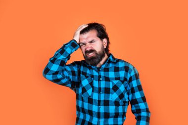 Kötü hissediyorum. Kareli gömlekli sakallı adam. Sıradan bir adam insani duygularını ifade eder. Uzun saçlı ve bıyıklı hipster 'ın başı ağrıyor. Erkek güzellik ve moda. Migren konsepti. Acı çekiyorum.