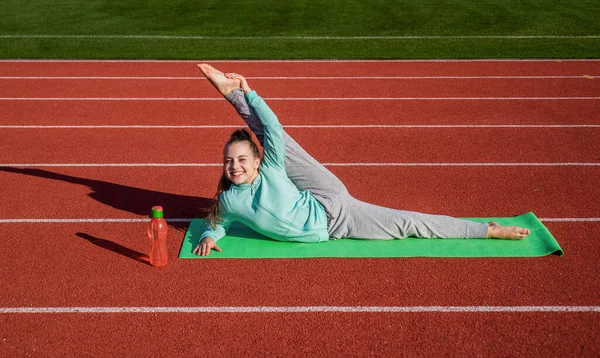 Chica niño entrenamiento deporte fuera en estadio arena split en yoga mat, salud —  Fotos de Stock