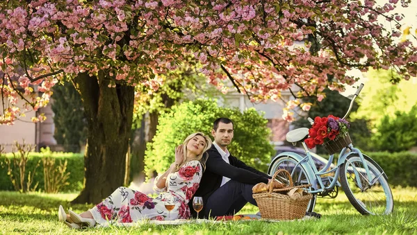 Happy loving couple relaxing in park with food. Romantic picnic with wine. Give uncommon, unique gifts spontaneously. Enjoying their perfect date. Couple in love picnic date. Spring weekend — Stock Photo, Image