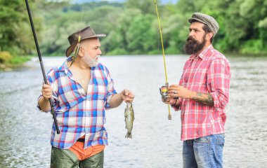 Çılgın hobiler. Uçan Balık Zamanı. Hobi. Gölün kıyısında kamp yapmak. Büyük balık avı. Arkadaşlık. Elinde olta ve ağla iki mutlu balıkçı. Turizm avcılığı. Baba oğul balık tutuyor.