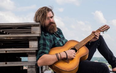 Müzik için mükemmel bir yer. Modern görünümlü sakallı, akustik gitarlı hippi. Bıyıklı vahşi yakışıklı adam gitar çalıyor. Olgun müzisyen ve şarkıcı. Sıradan stil gitarist.