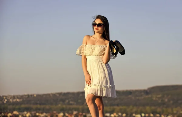 Vacanze estive. Ragazza in occhiali da sole copiare spazio. Verso l'estate. Concetto post-party. L'alba delle donne porta i tacchi alti in mano. Donna sul sole mattina cielo blu. Modello tenero abito estivo. Libertà — Foto Stock