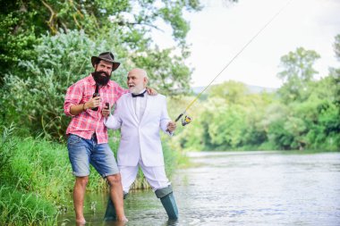 Oltayı oltaya getirin. Balık tutmak ve bira içmek. Sakallı adam ve zarif iş adamı birlikte balık tutuyor. Erkekler doğayı rahatlatıyor. Eğlen ve rahatla. Hafta sonu tatili. Balık tutma becerileri