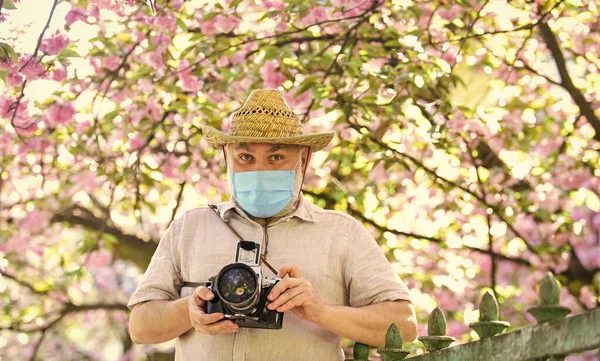 盛开摄影中的樱花。戴口罩的大胡子男子。专业摄影师在验尸检疫期间工作。男人用相机拍照樱花。好香 — 图库照片