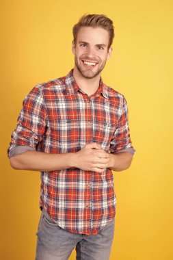 Sarı arka planda damalı tişörtlü mutlu adam. Seksi ve kendinden emin. Oğlan gündelik tarzda. Havalı saç stili olan berber. Gömlekli manken. Yaz ve bahar erkek koleksiyonu. Mutlu ol.