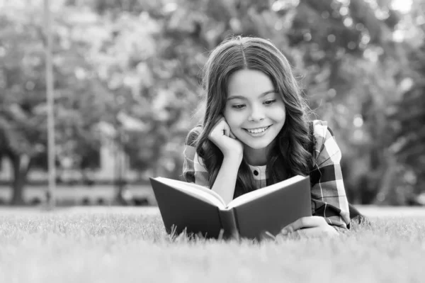 Para tener éxito debes leer. Un niño feliz leyó un libro sobre hierba verde. Biblioteca escolar. Educación de alfabetización. Lectura casera. Lección de literatura. Aprender lengua extranjera. Escuela de inglés. Vale la pena pasar tiempo —  Fotos de Stock