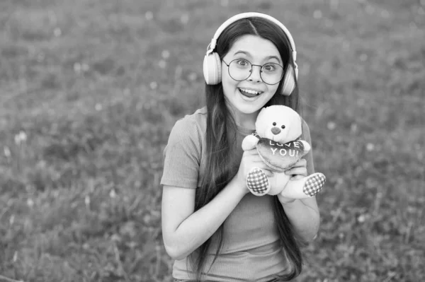 Juego de verano. Chica feliz jugar con el oso de peluche en la hierba verde. Juegos de infancia para jugar. Actividad al aire libre. Desarrollo y crecimiento infantil. Jugando con juguetes. Tienda de juguetes. Juega para desarrollar la imaginación — Foto de Stock