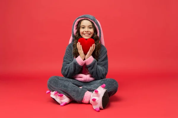 Criança feliz em pijama de coelho segurar coração vermelho presente salva-vidas, doação — Fotografia de Stock