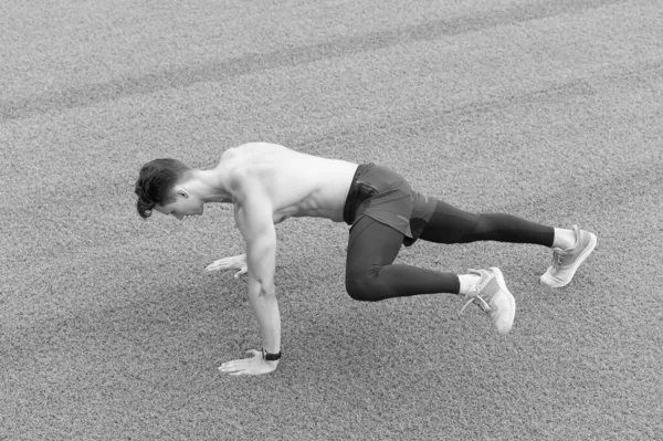 Atlético haciendo ejercicio de tablón. entrenamiento deportista muscular en césped verde. Corre mientras respiras. El atleta entrena duro su parte inferior y superior del cuerpo en la hierba. Formación sobre el aire fresco — Foto de Stock