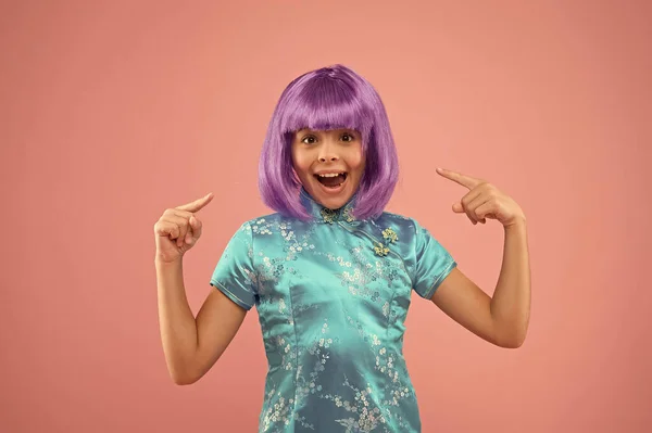 Me encanta mi nuevo cabello. Niña apuntando al pelo violeta. Un niño feliz usa una peluca de pelo elegante. Corte de pelo y color de pelo. Salón de belleza. Belleza y moda —  Fotos de Stock