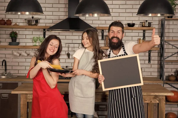 Een klein meisje met ouders die koken. Recept van een perfect familiediner. Moeder en vader met klein meisje met schoolbord kopieerruimte. Familietraditie. Gelukkige familie in de keuken. Aangename tijd samen — Stockfoto