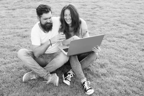 Online dating. Couple in love use laptop on green grass. Online access. Internet surfing. Online environment. New technology. Video call. Modern life. Both online and in real worl