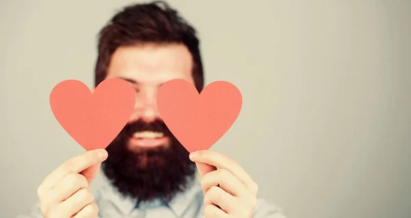 Allt han behöver är kärlek. Hipster täcker ögon med små hjärtan. Sexig valentinsk man med kärlekskort. Skäggig man med röda hjärtan. Glad Alla hjärtans dag. Uttrycka sin kärlek, kopiera utrymme — Stockfoto