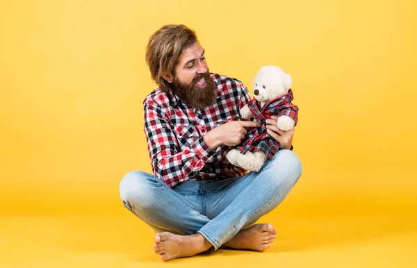 Brutal barbudo homem desgaste xadrez camisa ter exuberante barba e bigode com ursinho de pelúcia brinquedo, dia dos namorados — Fotografia de Stock