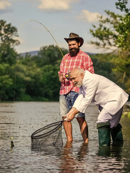 Tiempo libre. hobby del hombre de negocios. pesca de jubilación. amigos hombres con caña de pescar y red. padre jubilado e hijo barbudo maduro. pescadores felices. Buena ganancia. Aventuras de pesca con mosca —  Fotos de Stock