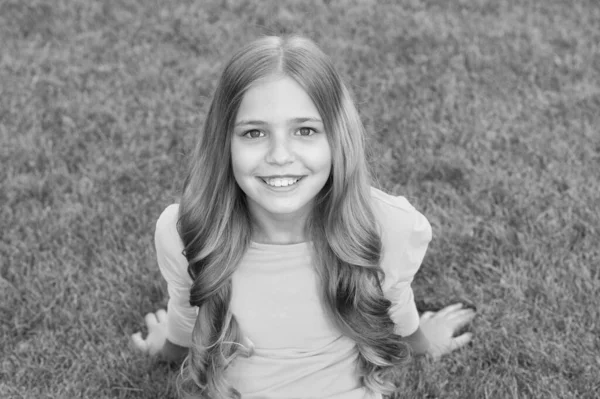 Χαρούμενο χαμογελαστό κοριτσάκι χαλαρωτικό πράσινο γρασίδι, ανέμελη έννοια της παιδικής ηλικίας — Φωτογραφία Αρχείου