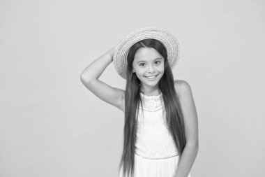 Yazın tadını çıkarıyorum. Uzun zamandır beklenen yaz tatili. Mutlu çocukluk. Neşeli küçük kız hasır şapka takıyor. Çocuklar için plaj modası. Sarı arka planda küçük bir çocuk. tatil eğlencesi ve aktivitesi. güzellik