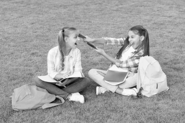 C'est l'heure de se détendre. s'amuser sur l'herbe verte. deux petits enfants avec sac à dos. petite fille jouer et étudier sur la pause scolaire. heureux jour des enfants. fraternité et concept de famille. jour de connaissance est venu — Photo