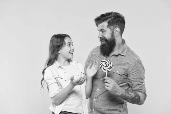 Gelukkig familie vader en dochter eten lolly gele achtergrond, eet snoep concept — Stockfoto