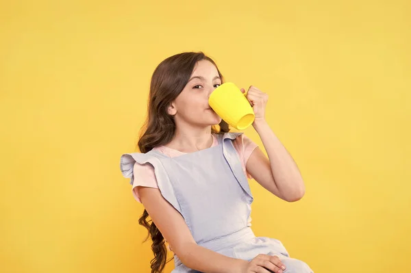 No es mi taza de té. Haciendo sorbos. Bebe suficiente agua. Niña sostiene la taza de fondo amarillo. Un niño encantador sostiene la taza. Beber cacao de jugo de té. Relajarse con la bebida. Bebida infantil. Hábitos saludables —  Fotos de Stock