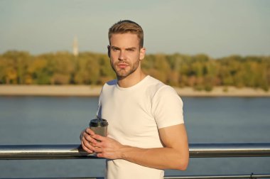 Her sabah bir fincan güneş ışığı yeni bir güne başlamaya yardımcı olur. Genç adam sabahları hazır kahve içer. Nehir kıyısındaki sıcak bardağın tadını çıkarıyorum. Sabah alışkanlığı. Uyanın. Uyanın. Günaydın yaz.