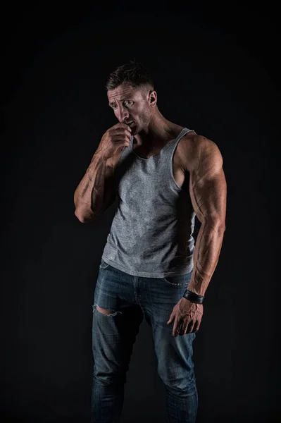 Infelice culturista indossare maglietta casual con jeans mostrando forti braccia muscolari bicipiti tricipiti muscoli sfondo nero, bodybuilding — Foto Stock