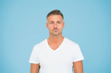 Süper adam. Soyut mavi arka plan. Beyaz orta yaşlı bir adam. Sıradan tarzda yakışıklı bir adam. Moda ve tarz. Sakallı, tıraşsız bir adam. Berber dükkanı. Kuaför salonu.