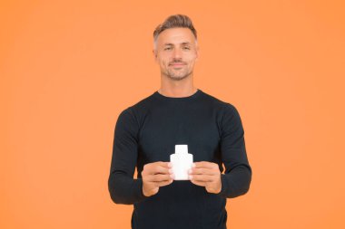 Tıraşsız yüzü ve şık saçı olan yakışıklı beyaz adam parfüm şişesi sarı arka plan, cilt bakımı