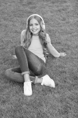 Şirin gülümseyen kız modern kulaklıklar müziği sever açık havada dinlenir, dijital ses konsepti