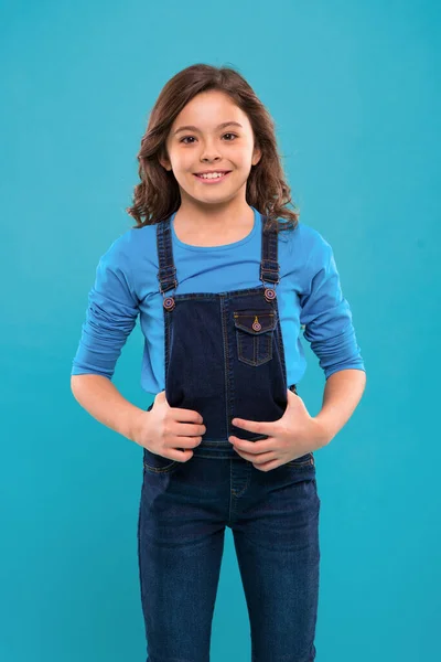 Pura belleza. Niña con el pelo largo. Niño feliz cara linda con adorable pelo rizado de pie sobre fondo azul. Consejos de belleza para el cabello ordenado. Niña larga y saludable pelo brillante desgaste ropa casual —  Fotos de Stock