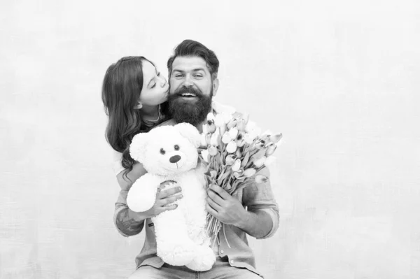 Fader, jag älskar dig. Lycklig dotter kysser far. Skäggig man och litet barn håller blommor och leksak. Trevlig familjesemester. Kärlek och omsorg. Födelsedag. Pappadagen. Gratulerar! — Stockfoto