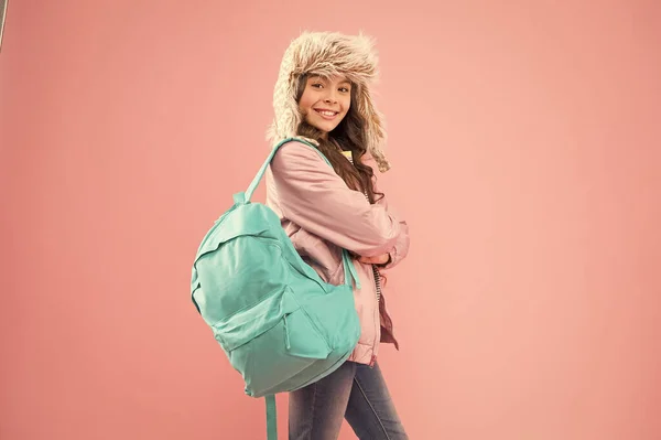 Successful Everyday. kid warm clothes pink background. happy child earflap hat. schoolgirl with backpack. end of school year. no more exams. small happy girl back to school. winter holiday vacation